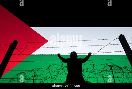 Zusammengesetztes Bild eines Mannes, der Felsen über einen Stacheldrahtzaun wirft, mit der Flagge Palästinas im Hintergrund. Grenzkontrolle, Naher Osten, Protest... Konzept. Stockfoto