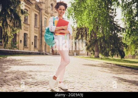 In voller Länge Foto von glücklich schön dunkle Haut Frau tragen Rucksack halten Notebooks Hochschule draußen Stockfoto