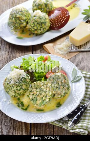 Hausgemachte traditionelle Südtiroler Spinatknödel aus Weißbrot und frischen Spinatblättern, serviert mit geschmolzener Salbeibutter und geriebenem Parmesan Stockfoto