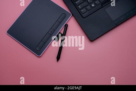 Draufsicht auf schwarze Stiftmaus, digitales Tablet und Laptop für Grafikdesign auf rosa Hintergrund. Obere Ansicht des Stift-Grafiktabletts. Gadget Stockfoto