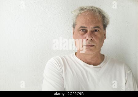 Porträt eines reifen Mannes mit grauen Haaren in weißem Hemd auf weißem Hintergrund Stockfoto