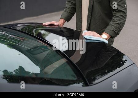 Beschnittene Ansicht des Mannes, der einen Lappen hält, während er den Kofferraum abwischt Stockfoto