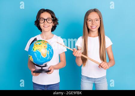 Foto Porträt Schuljunge Schülerin tun Hausaufgaben halten Globus Zeiger isoliert pastellblau Farbe Hintergrund Stockfoto