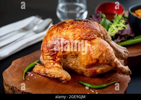 Gebratenes ganzes Huhn auf Holzkohle mit Bulgur-Pilaf auf Holzbrett gekocht. Stockfoto