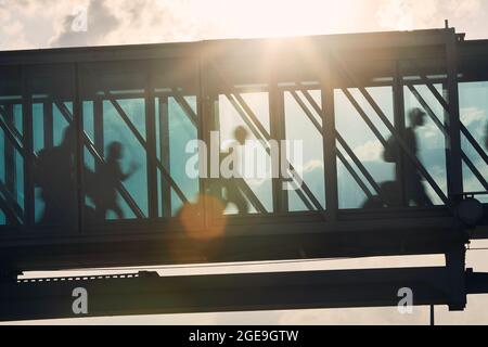 Silhouetten von Menschen, die am geschäftigen Flughafen laufen. Passagiere, die in die Bordbrücke gehen. Stockfoto