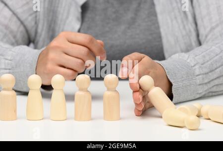 Hand stoppt den Fall von Figuren von Männern auf weißem Hintergrund. Konzept einer starken und mutigen Persönlichkeit, die ungleichen difficu standhalten kann Stockfoto