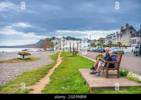 Zwei Rentner lesen auf einer Bank am Meer. Stockfoto