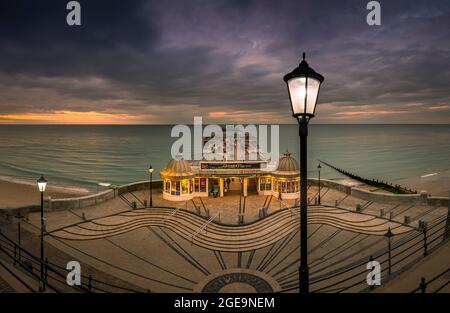 Die strassenbeleuchtung Start auf, wie die Sonne in Cromer Pier zu kommen. Stockfoto