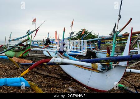 Outrigger Fischerboote (Jukungs) liegen am Strand in der Nähe von Pemuteran, Nordwestküste von Bali, Indonesien. Stockfoto