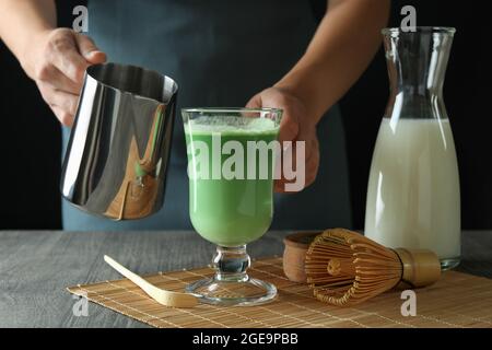 Frau macht Matcha Latte auf einem grauen texturierten Tisch Stockfoto