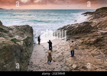 Abendlicht, als vier junge Männer am Strand in einer kleinen Bucht bei Little Fistral in Newquay in Cornwall stehen. Stockfoto