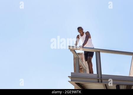 Von unten zeigt der afroamerikanische fit-Athlet auf der Terrasse Stockfoto