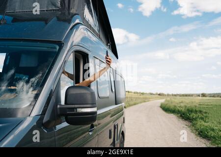 Unglückliche junge afroamerikanische Reisende, die auf dem Fahrersitz im Wohnmobil sitzt und versucht, eine Verbindung über das Mobiltelefon zu bekommen, während sie Probleme hat Stockfoto