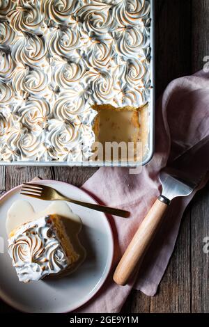 Von oben drei Milchkuchen in Backform und Teller mit Tassen starken Kaffee auf Holztisch Stockfoto
