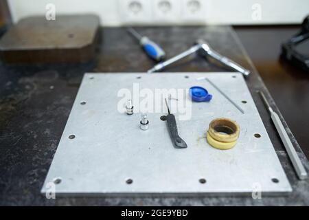 Hoher Winkel von verschiedenen Instrumenten auf Metallplatte in der professionellen Reparaturwerkstatt platziert Stockfoto