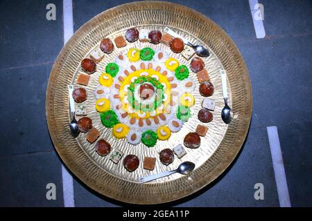 Schöner Kuchen aus buntem Reis, verziert mit trockenen Früchten und Süßigkeiten in Messingplatte Stockfoto