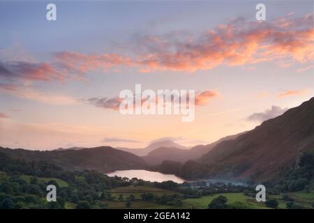 Bunte Wolken über dem Llyn Gwynant See bei Sonnenuntergang. Stockfoto