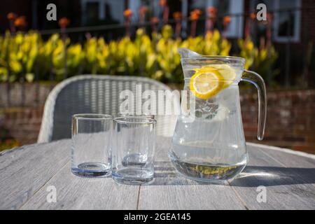 Erfrischender Wasserkrug mit Obstscheiben und zwei Gläsern Stockfoto