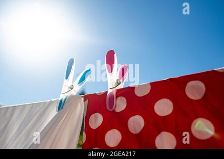 Zwei bunte Stifte halten die Wäsche bei strahlendem Sonnenschein an einer Linie. Stockfoto