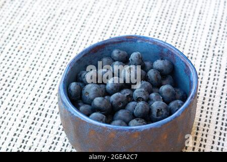 Nahaufnahme von frischen reifen Blaubeeren in einer blauen Keramik-Vintage-Tasse auf hellem Hintergrund. Speicherplatz kopieren. Vegetarisches Frühstück Stockfoto