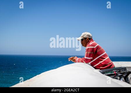 Zambujeira do Mar, Portugal - 28. Juni 2021: Portugiesischer Mann, der am Meer nach vorne blickt Stockfoto