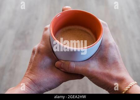 Eine Frau, die eine Tasse frisch gebrühten Kaffee in der Hand hält. Stockfoto