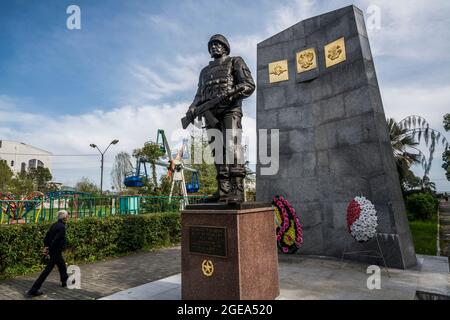 Ein Mann geht unter ein Denkmal für russische Friedenstruppen in Sukhum in Abchasien. Stockfoto