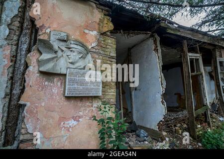 Eine Gedenktafel erinnert an die jetzt zerstörte ehemalige Residenz eines Helden des russischen Bürgerkrieges in Abchasien. Stockfoto