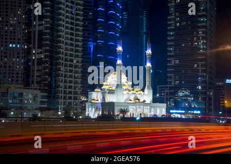 Die alten und modernen kollidieren in der futuristischen Stadt Dubai als Verkehr wirbelt Vergangenheit einer der vielen Moscheen. Stockfoto