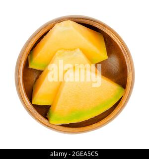 Honigmelone in Scheiben, in einer Holzschale. Dreieckige, verzehrfertige Stücke frisch geschnittener, reifer Früchte. Hybridmelone der Art Cucumis melo. Stockfoto