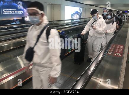 Hongkong, China. August 2021. Passagiere tragen am Mittwoch, den 18. August 2021, eine Ganzkörperschutzausrüstung (PSA) auf dem Weg durch den internationalen Flughafen von Hongkong. Hongkong ist angesichts der Gefahr eines neuen Covid-Ausbruchs weiterhin auf hoher Alarmstufe, da es nach wie vor ein wichtiger Knotenpunkt und Reiseziel in Asien ist. Foto von Stephen Shaver/UPI Credit: UPI/Alamy Live News Stockfoto