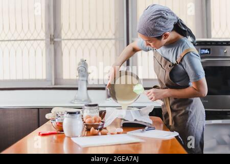 Bäcker Tortenmischung in eine Kuchenform mit Papier zum Backen von Käsekuchen gießen. Stockfoto