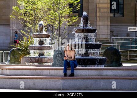 Dundee, Tayside, Schottland, Großbritannien. August 2021. UK Wetter: Spätsommer-Hitzewelle fegt über Nordostschottland mit Temperaturen von bis zu 24 Grad Eine glamouröse junge Frau Annette Clarke, die im Schatten sitzt und sich von dem herrlich heißen, sonnigen Wetter an den Caird Hall Fontänen im Stadtzentrum von Dundee abkühlt. Kredit: Dundee Photographics/Alamy Live Nachrichten Stockfoto