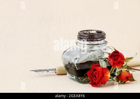 Tintenfass, Feder und getrocknete Rosen auf Vintage-Papier Hintergrund. Speicherplatz kopieren. Stockfoto