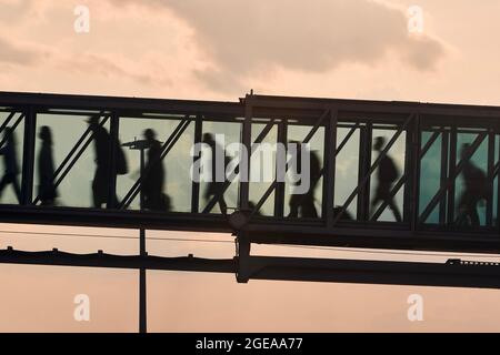 Silhouetten von Menschen, die am geschäftigen Flughafen laufen. Passagiere, die in die Bordbrücke gehen. Stockfoto