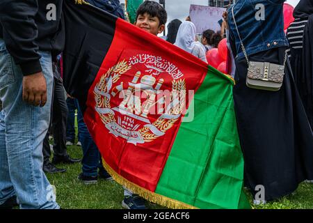 WESTMINSTER LONDON 18. August 2021. Ein junges Mitglied der britischen afghanischen Gemeinschaft steht auf dem Parliament Square hinter der Flagge der ehemaligen Regierung Afghanistans, als Reaktion auf die Machtannahme der Taliban in Afghanistan. Premierminister Boris Johnson hat sich an das Parlament erinnert, als die MPS aus ihrer Sommerpause zurückkehrt, um die Krise in Afghanistan zu debattieren und 20,000 gefährdete afghanische Flüchtlinge zu bringen. Credit amer Ghazzal/Alamy Live News Stockfoto