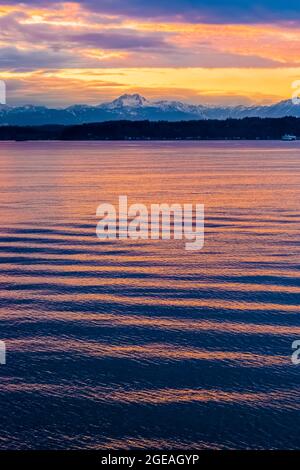 Wintersonnengang über der Elliot Bay of Puget Sound mit der fernen Bainbridge Island und den Olympic Mountains, von der Bremerton Ferry aus gesehen, Washington State, Stockfoto