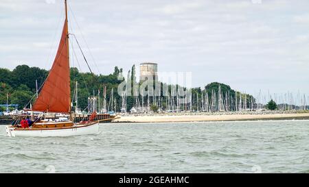 Shotley, Suffolk - 18. August 2021: Rot gesegelte Yacht verlässt die Marina. Stockfoto