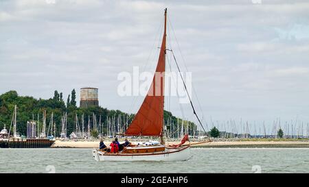 Shotley, Suffolk - 18. August 2021: Rot gesegelte Yacht verlässt die Marina. Stockfoto