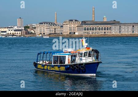 Cremyll, Cornwall, England, Großbritannien. 2021. Passagiere an Bord einer kleinen Fähre, die zwischen Plymouth und Cremyll mit dem Hintergrund der Royal William Yard fährt Stockfoto