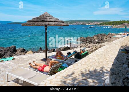 Urlauber sonnen sich an einem typischen Badeplatz an der Felsküste bei Krk in Kroatien Stockfoto