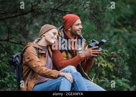 Glückliche Frau, die sich auf einen Mann stützt, der im Wald eine Vintage-Kamera hält Stockfoto