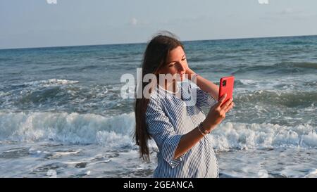 Junge Frau beim Selfie am Meer. Stockfoto