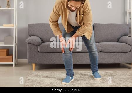 Junger Mann, der an Arthritis oder Rheuma leidet, versucht zu gehen, aber er spürt Schmerzen im Knie Stockfoto