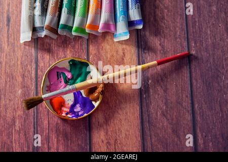 Tempera-Farben auf dem Holztisch in einer Werkstatt, selektiver Fokus, Satz von Aquarellfarben, und ein Pinsel für Malerei und Palette. Horizontal Stockfoto