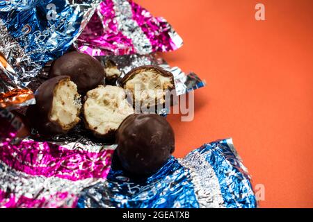 Einige Pralinen und verschiedene bunte Verpackungen auf orangefarbener Oberfläche Stockfoto