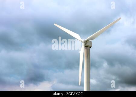 Windmühlen für die Stromerzeugung. Windturbine vor dem Hintergrund eines dunklen düsteren Himmels, windiges Wetter, Ort, um Text einzufügen. Stockfoto