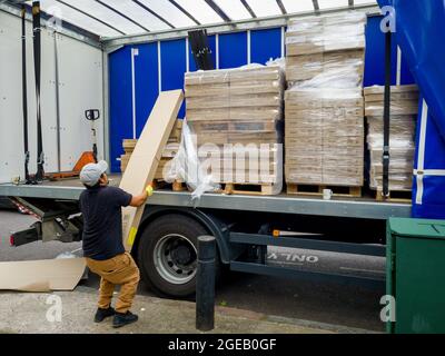 London. Großbritannien- 08.13.2021: Arbeiter entladen schwere Pakete von einem schweren Güterwagen. Stockfoto