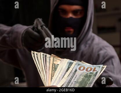 Bewaffneter Raub, Dieb mit einer Pistole in der Hand, Mann in einer Sturmhaube droht mit einer Waffe, um Geld zu stehlen, Nahaufnahme. Stockfoto