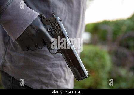 Bewaffneter Mann, der sich bewegt, eine Pistole in seiner Hand hält, verwischt den Hintergrund der Natur im Freien. Konzept von Bedrohung, Gewalt und Gefahr Stockfoto